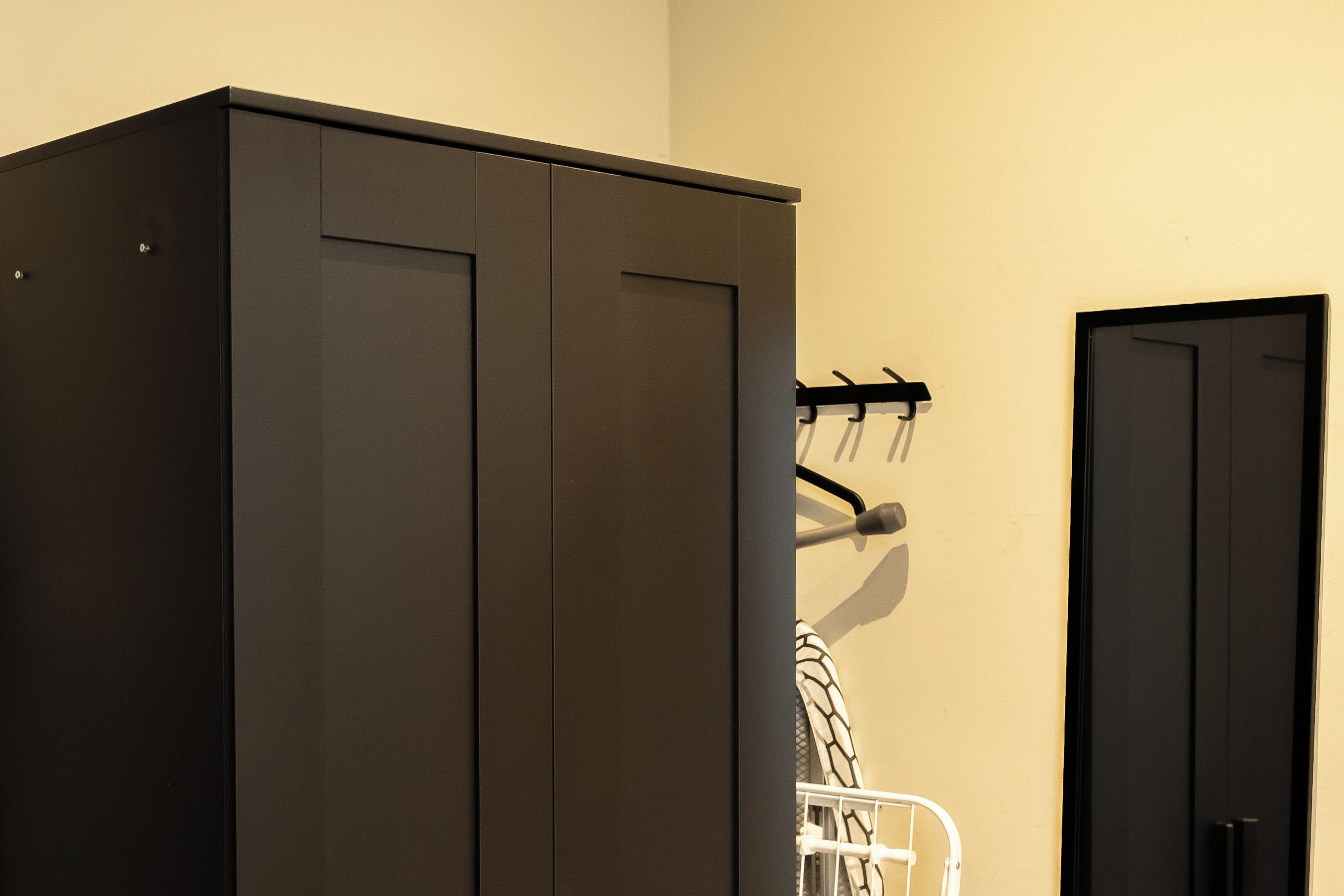 Habitació amb un armari gran, una porta i un penjador amb un abric.