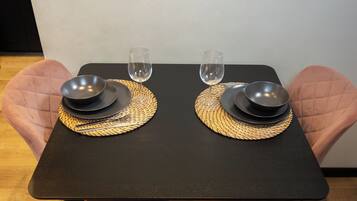 Una mesa con dos platos negros, una copa de vino y un bol sobre individuales tejidos.
