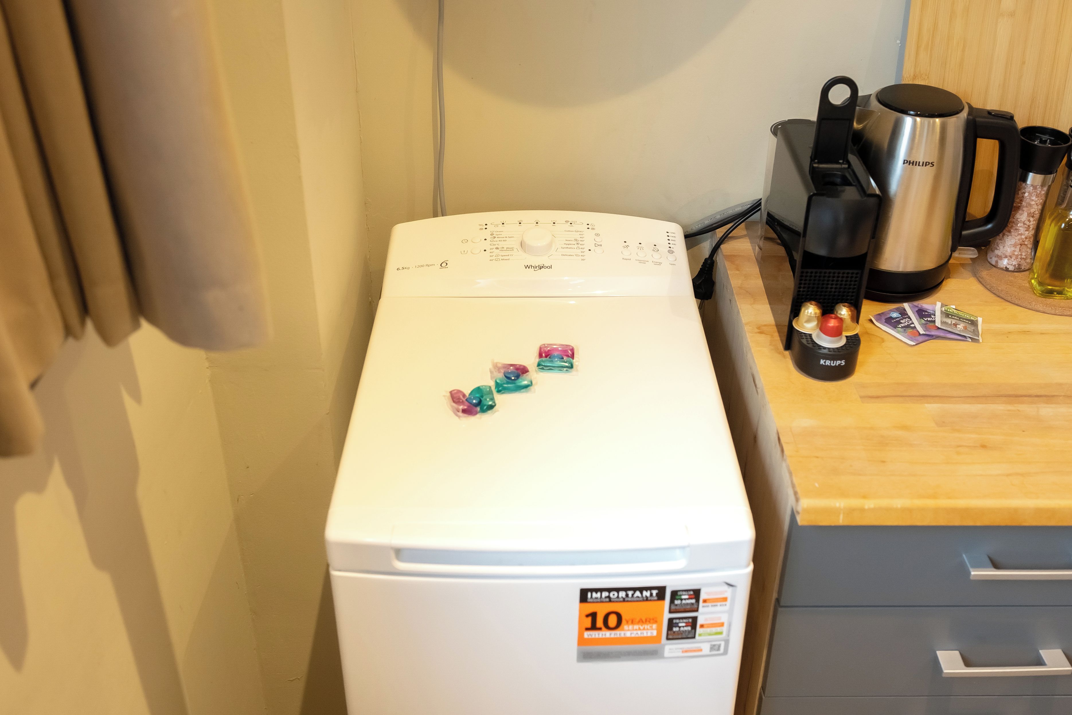 A white refrigerator with a control panel, a coffee maker, and a kettle on the countertop.