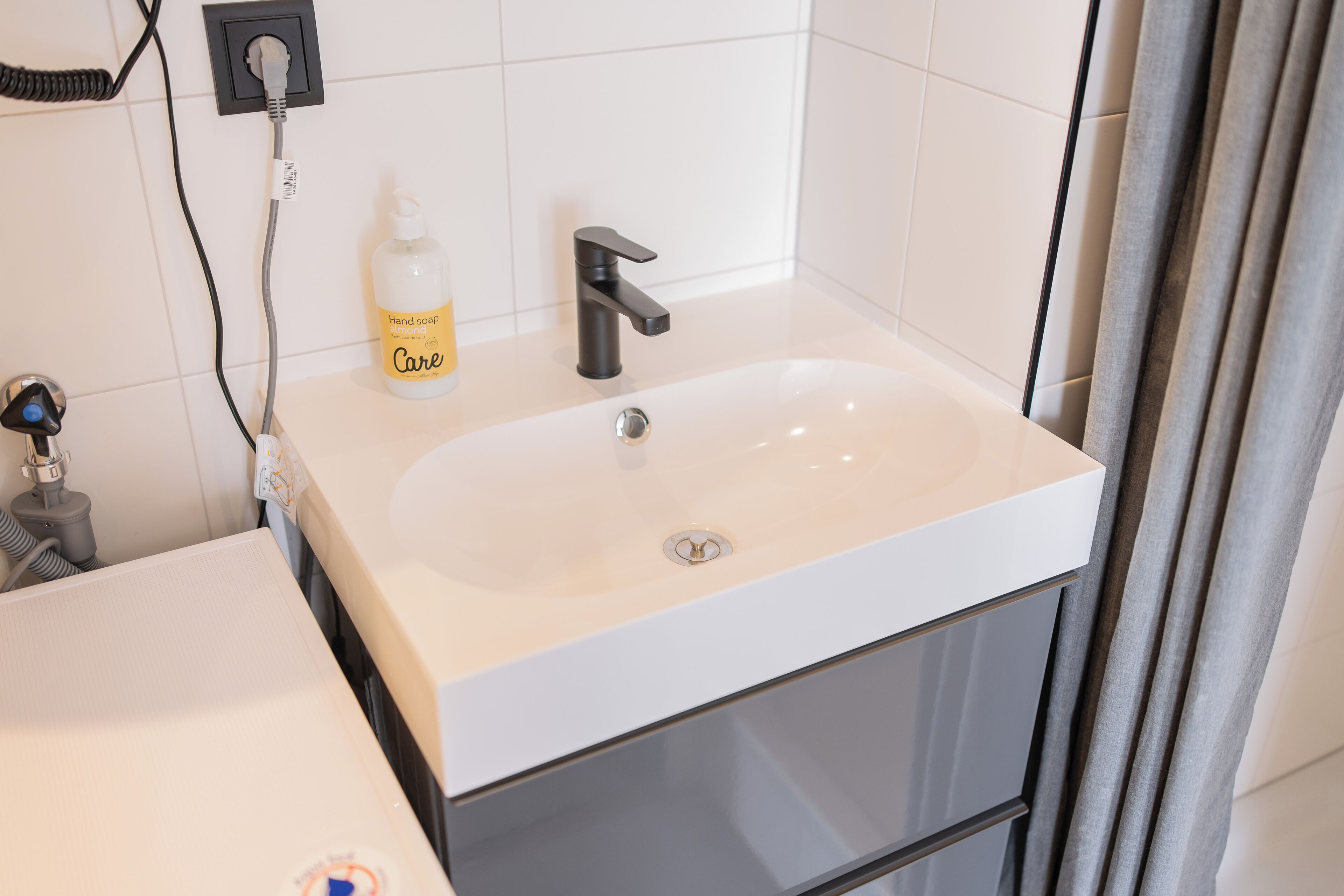 A bathroom with a white sink, black faucet, and a bottle of hand soap.