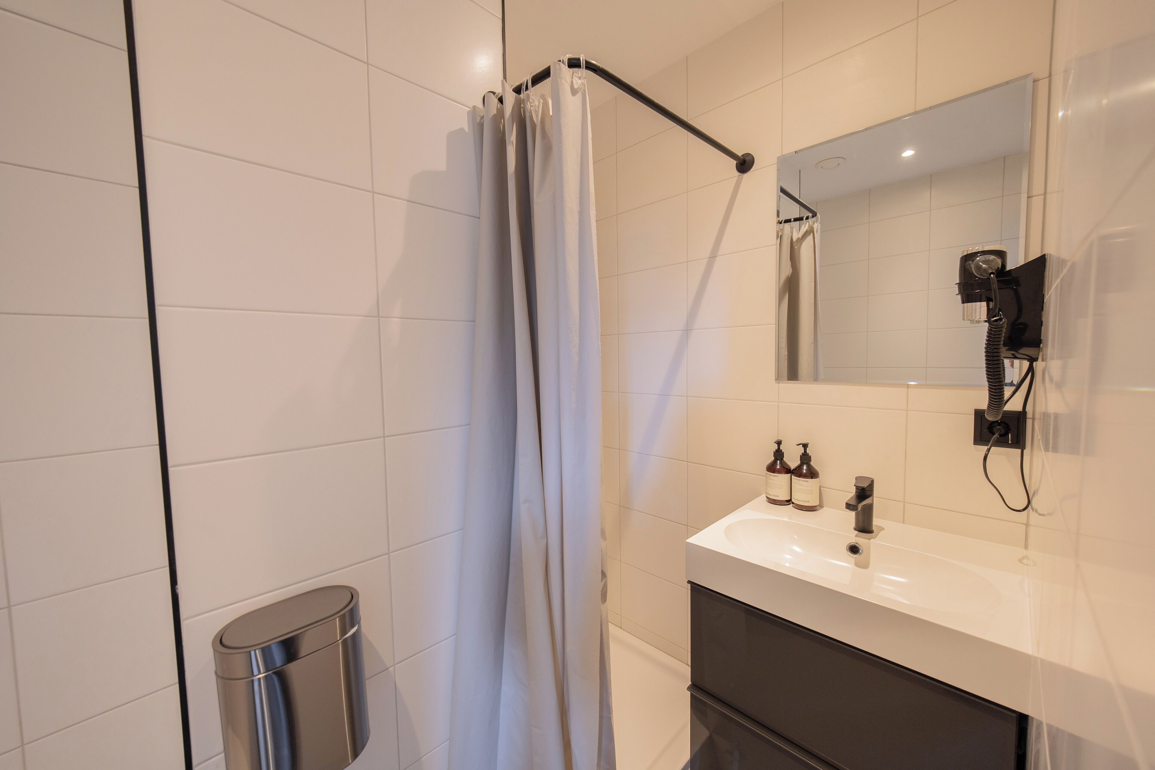 A modern bathroom with a shower, a sink, and a mirror.