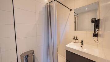 A modern bathroom with a shower, a sink, and a mirror.