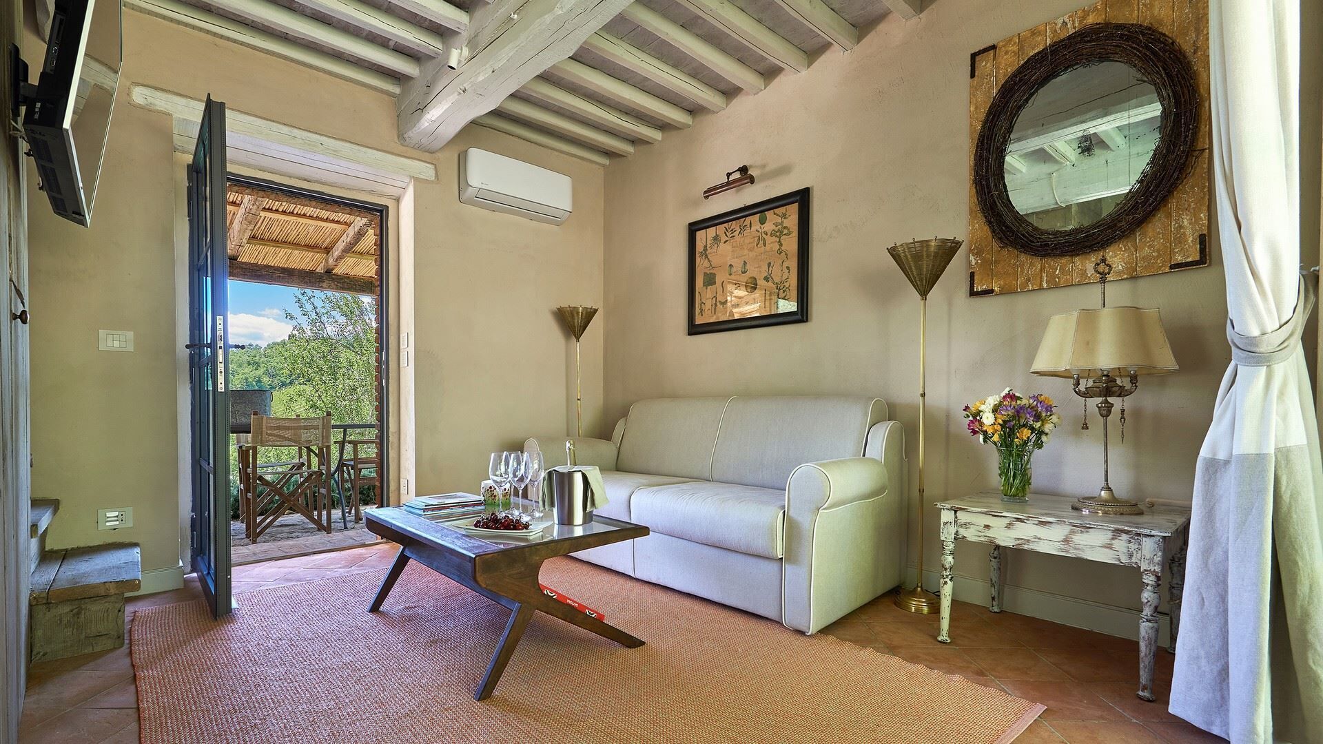 A living room with a white sofa, a coffee table, a floor lamp, and a decorative mirror.