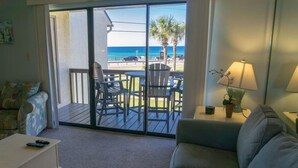A room with a sliding glass door leading to a deck with outdoor seating and a view of the beach. - Blue Surf 2 (Miramar Beach)