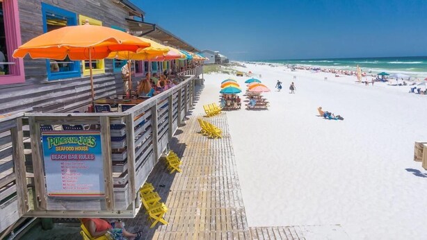 A wooden beach bar with colorful umbrellas and a sign listing beach rules. - Blue Surf 2 (Miramar Beach)