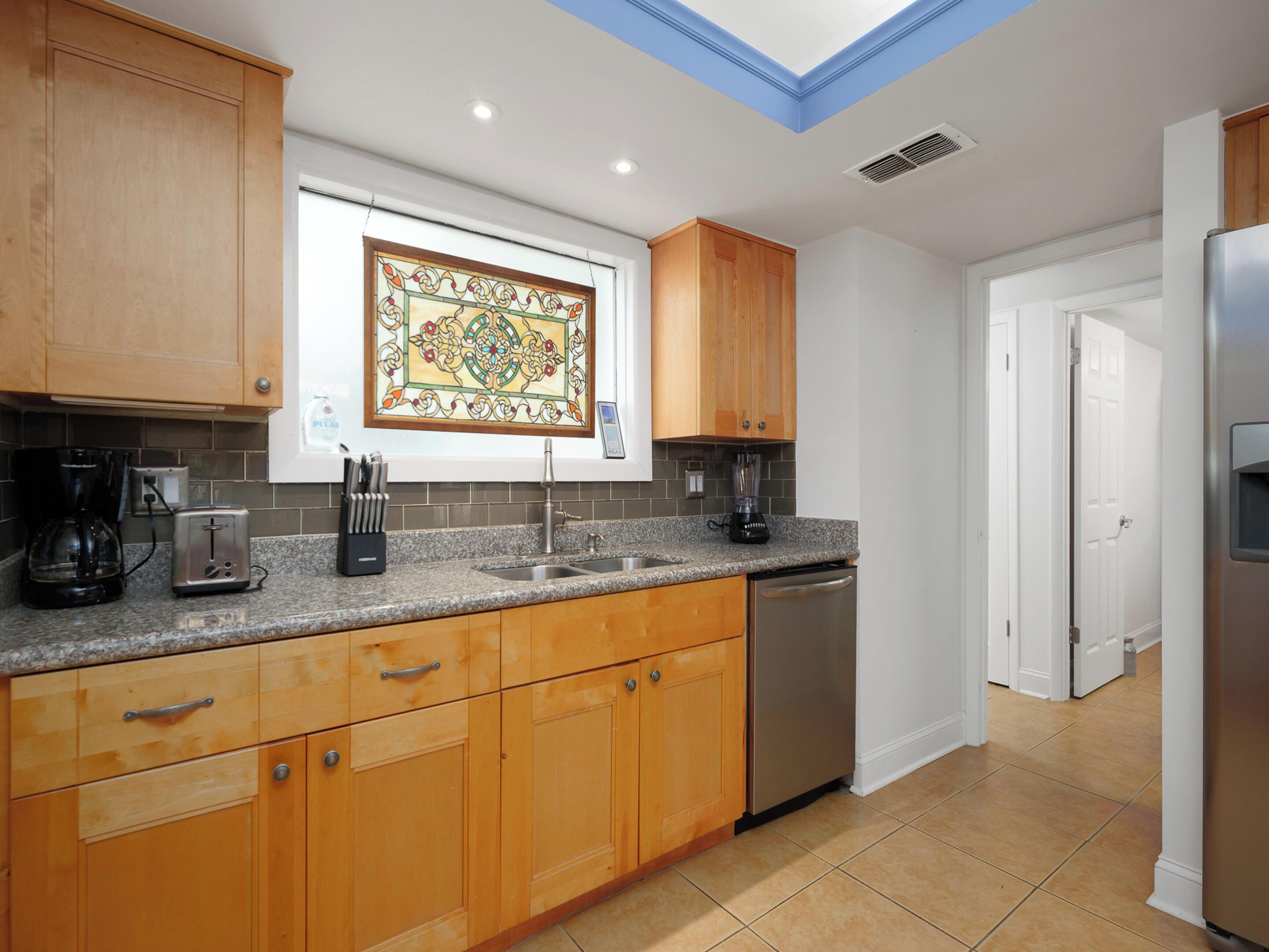 A modern kitchen with wooden cabinets, a granite countertop, a coffee maker, a toaster, and a blender.