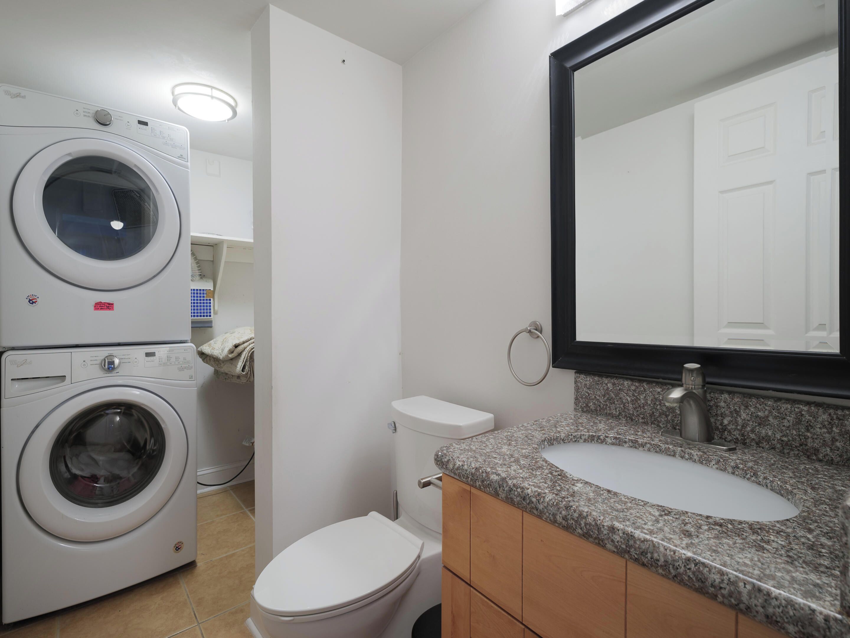 A compact bathroom with a washing machine, toilet, and sink.