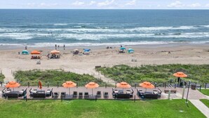 A beach with lounge chairs and umbrellas, a boardwalk, and a view of the ocean. - Chic Stay by the Beach (South Padre Island)