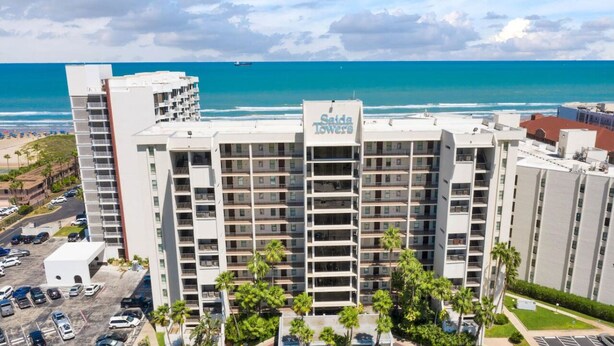 Un hotel de gran altura llamado 'Saida Towers' con varios balcones, un estacionamiento y vista a la playa y al océano.