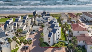 Una zona residencial costera con edificios modernos, una playa y una vista despejada del océano.