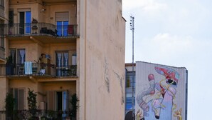 A multi-story building with balconies, a mural on the side, and a clear sky. - Artists Art Apartment (Torino)