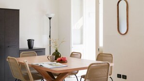 A dining area with a wooden table, wicker chairs, a vase with flowers, and a potted plant. - Artists Art Apartment (Torino)
