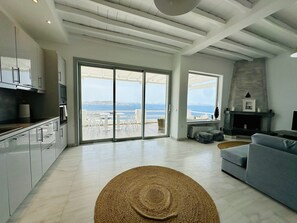A spacious living area with a large sliding glass door leading to a balcony with a view of the sea. - Seaview & Jacuzzi (Mykonos)