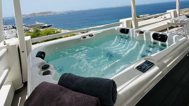 Un bain à remous avec vue sur la mer, une pergola et une serviette.