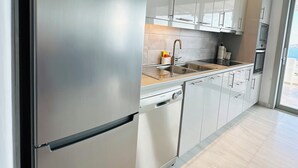 Une cuisine moderne dotée d’appareils électroménagers en acier inoxydable, de meubles blancs et d’un four encastré.