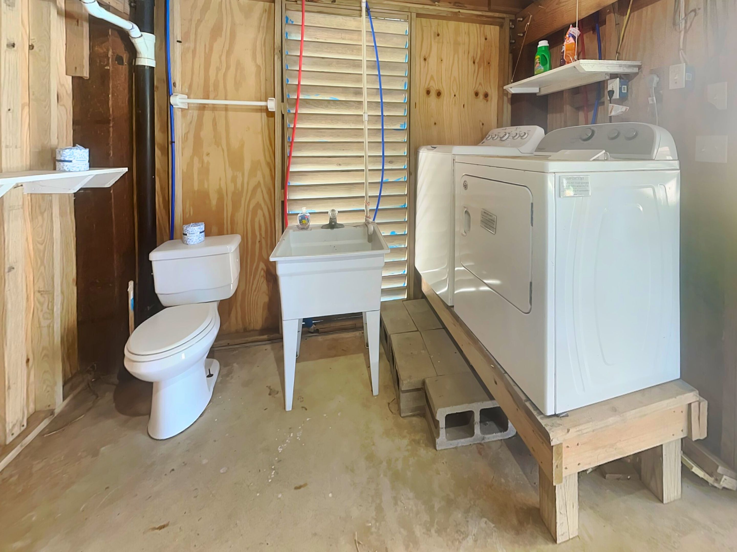 A compact bathroom with a toilet, a small sink, and a white washing machine.