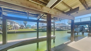 A wooden dock with a view of a marina and houses in the background. - Bayview Cottage by Ryson Vacation Rentals (Galveston)