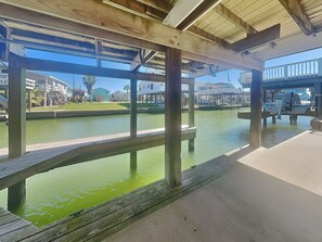 A wooden dock with a view of a marina and houses in the background. - Bayview Cottage by Ryson Vacation Rentals (Galveston)