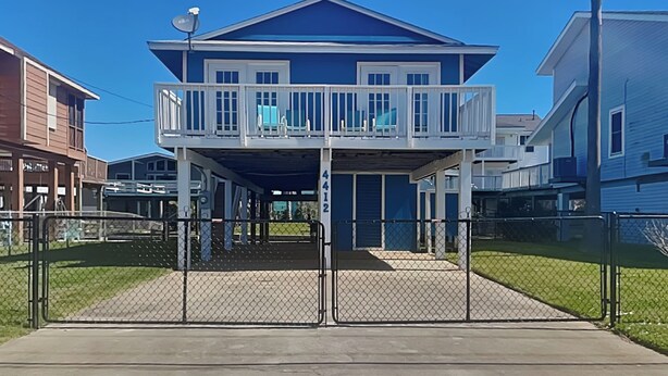 A two-story residential building with a balcony on the upper floor. - Bayview Cottage by Ryson Vacation Rentals (Galveston)