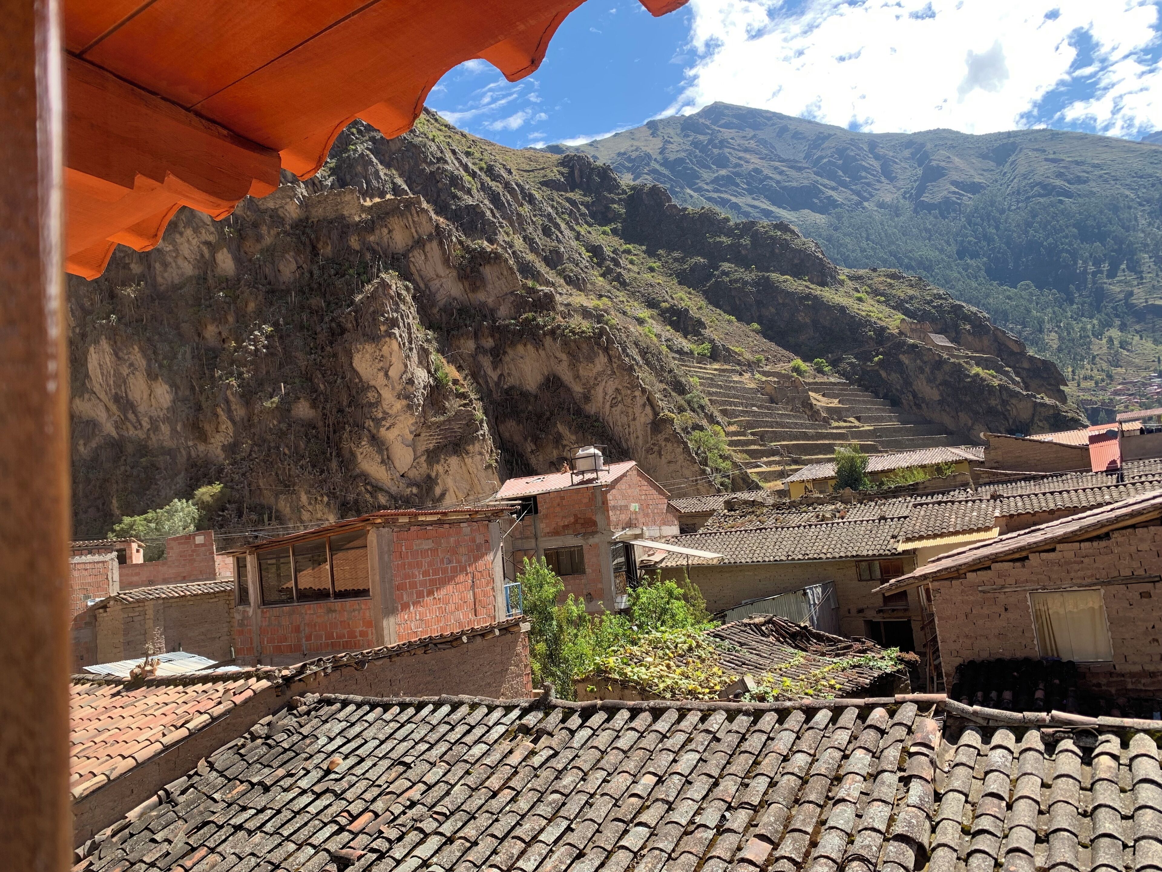 Un poble de muntanya amb camps en terrasses i edificis tradicionals amb teules vermelles.
