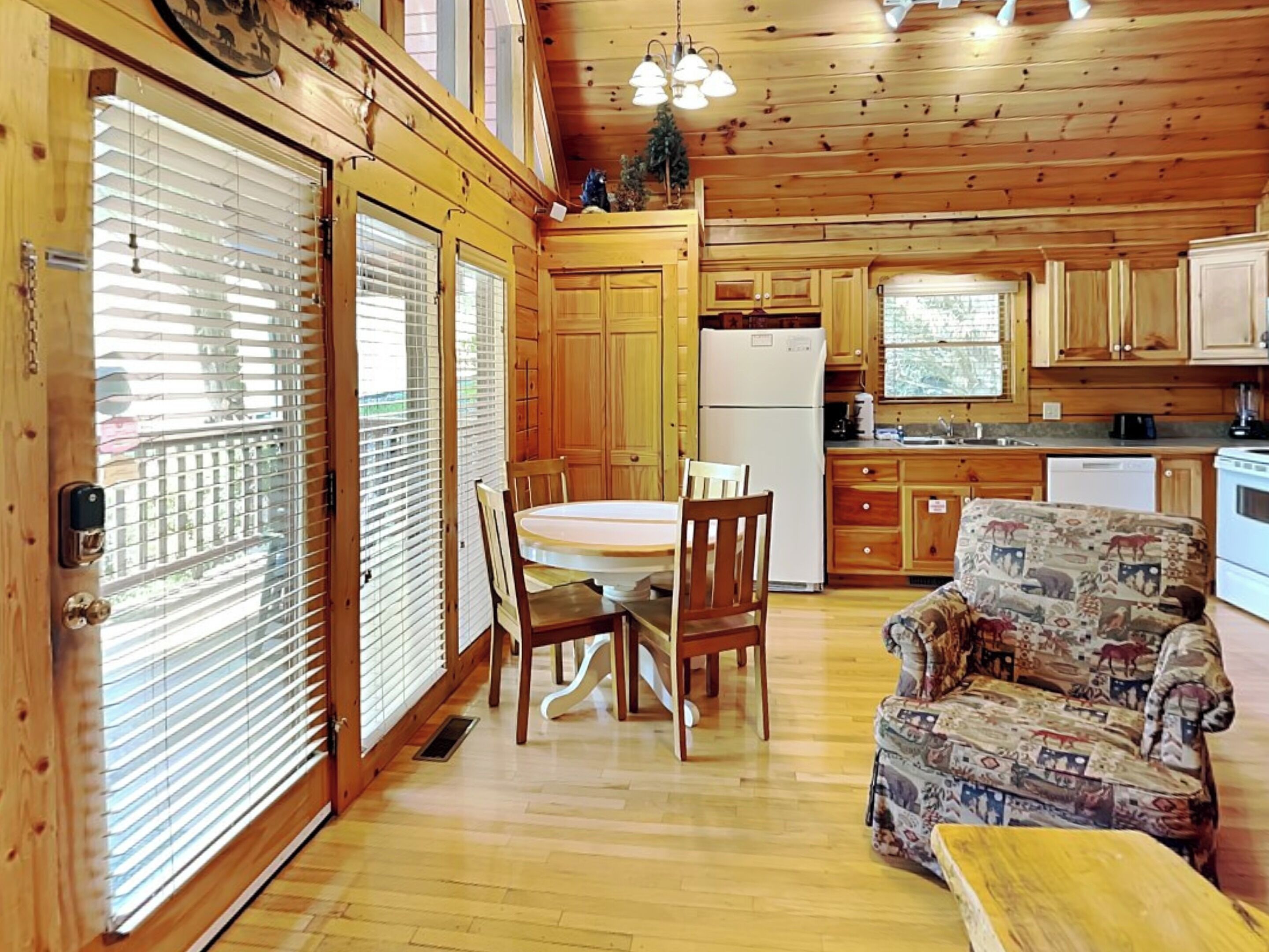 L’intérieur d’un chalet en bois comprend un coin repas, une cuisine et un canapé à motifs.