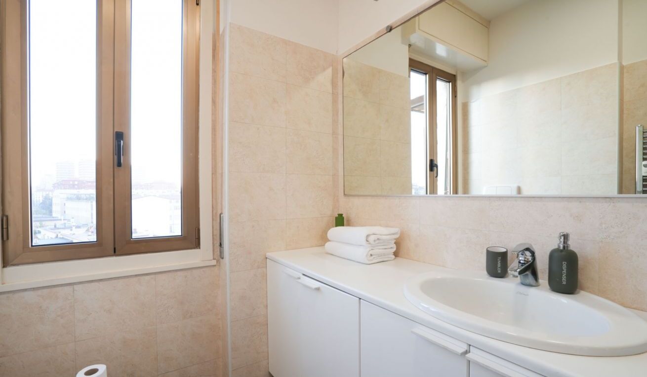 Ein modernes Badezimmer mit großem Fenster, Waschbecken, Spiegel und Schrank.