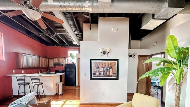 A modern living space with a kitchen, a dining area, and a seating area with a sofa and armchair. - Sleepover | Extraordinary 2BD/1BA Condo - SGF (Springfield)