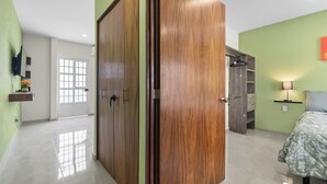 Een kamer met een houten garderobe, een bed met een bloemenprint en een wandtelevisie, en een plank met bloemen.