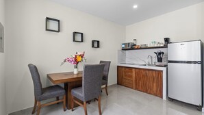 Een moderne keuken met een eetgedeelte, met een houten tafel, grijs gestoffeerde stoelen, een marmeren aanrechtblad en een inbouwkoelkast.