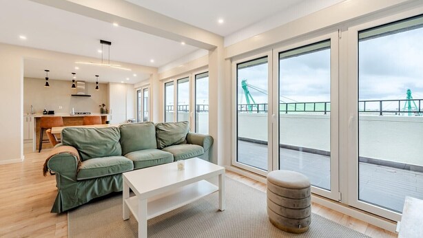 A modern living room with a green sofa, a white coffee table, and a view of a bridge.