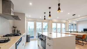 A modern kitchen with a central island, stainless steel appliances, and pendant lighting.