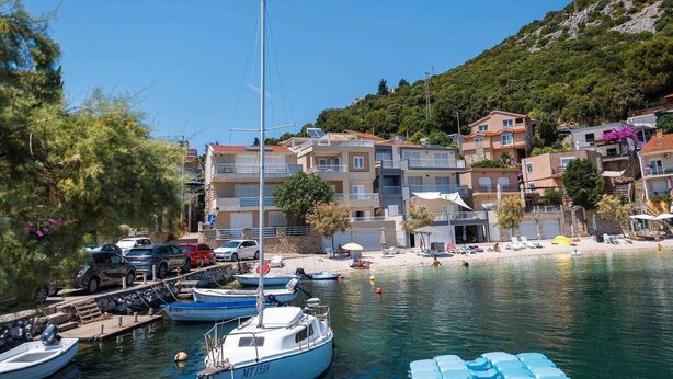 A coastal town with a marina, boats, and buildings with balconies overlooking the water. - Apartment Spajic by aneo travel (Klek)