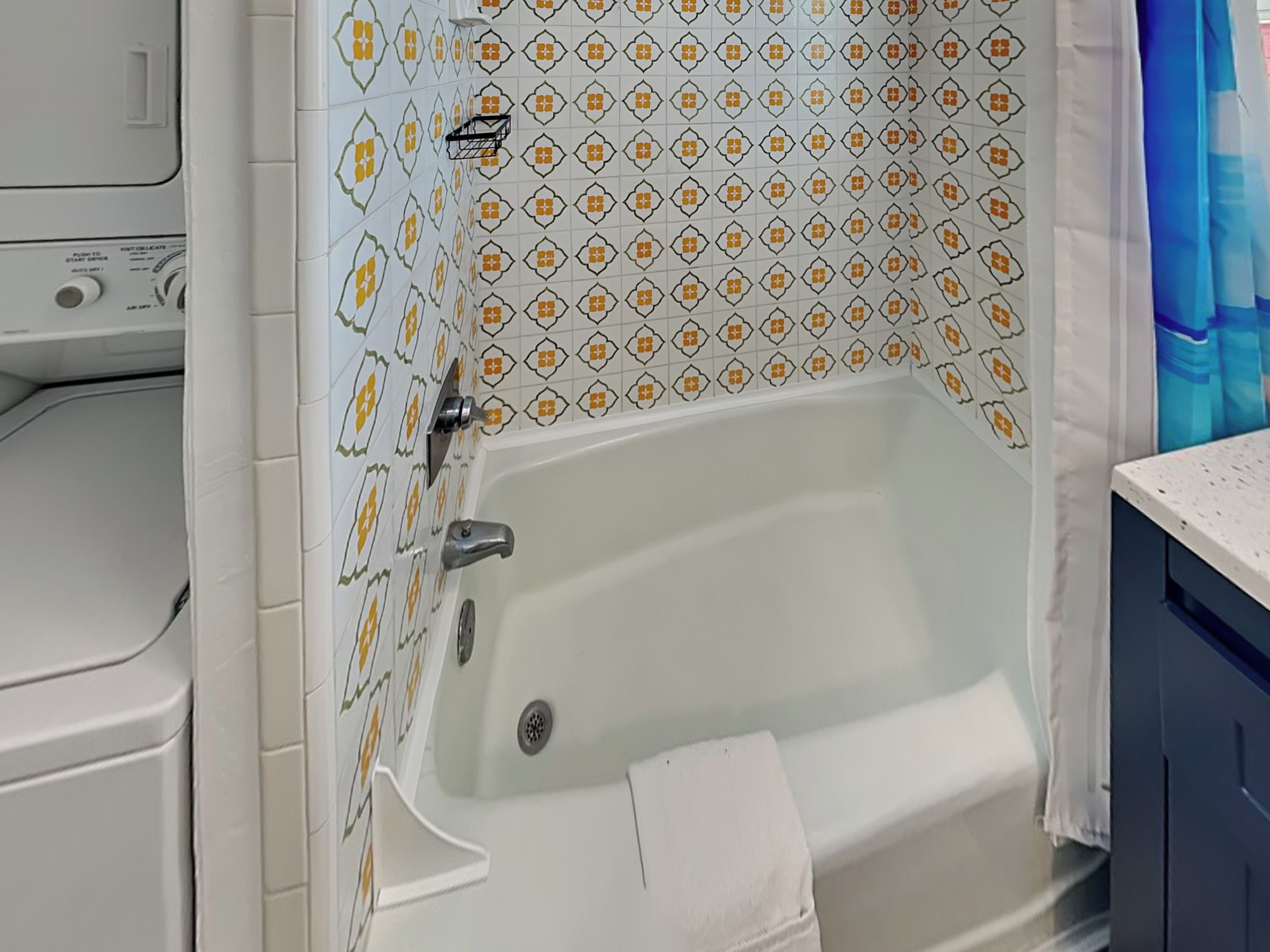 A bathroom with a white bathtub, a towel rack, and patterned tiles.