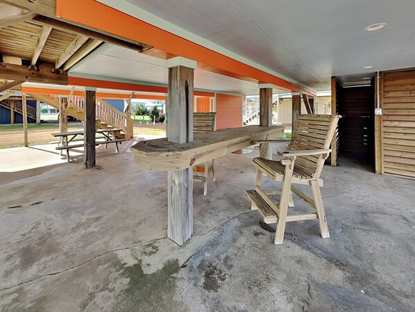 An outdoor seating area with wooden benches and a concrete floor. - Once Upon a Tide by Ryson Vacation Rentals (Galveston)