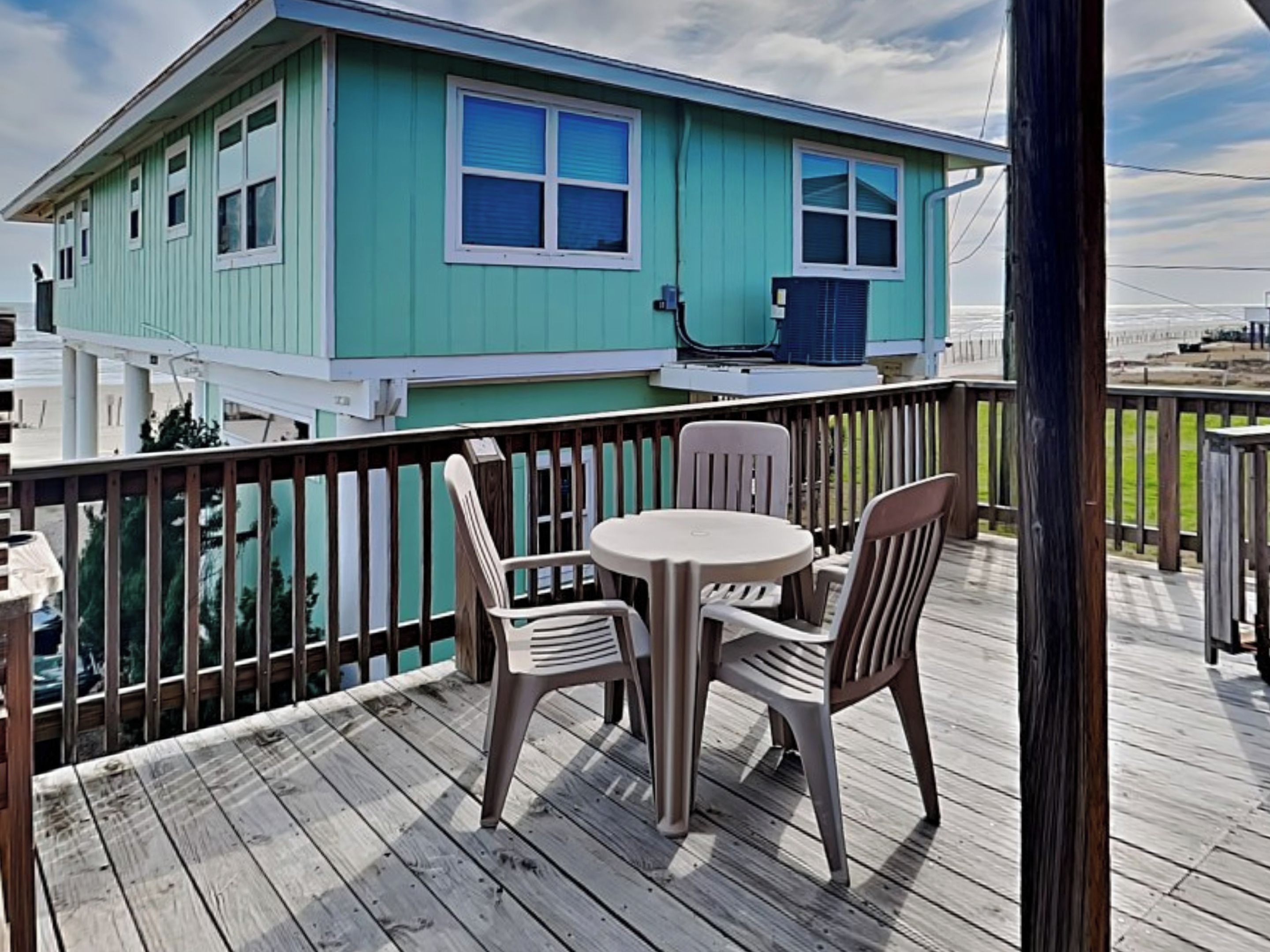 A turquoise house with a balcony, a round table, and two chairs.