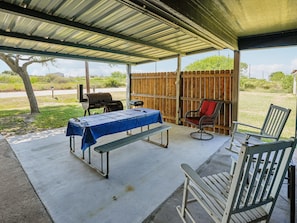 A covered patio area with a table, chairs, and a grill. - Sorry Charlie's by Miss Kitty’s (Rockport)