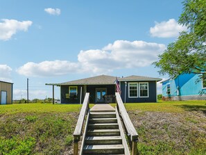 Ein Haus mit einer Veranda, einer Flagge und einer Holztreppe, die zum Eingang führt.
