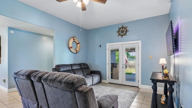 A room with a massage chair, a ceiling fan, a door with glass panels, a wall-mounted decoration, and a small table with a lamp. - Sorry Charlie's by Miss Kitty’s (Rockport)