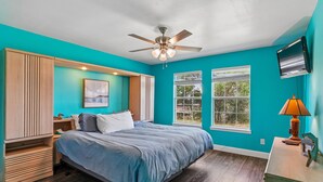 A bedroom with a bed, a ceiling fan, a window, and a TV. - Sorry Charlie's by Miss Kitty’s (Rockport)