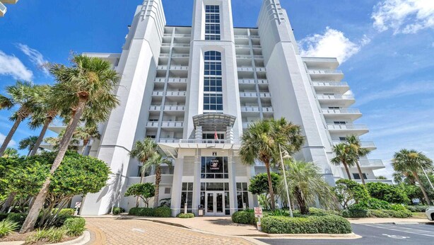 Un hotel moderno con un atrio central, varios pisos y una entrada destacada.