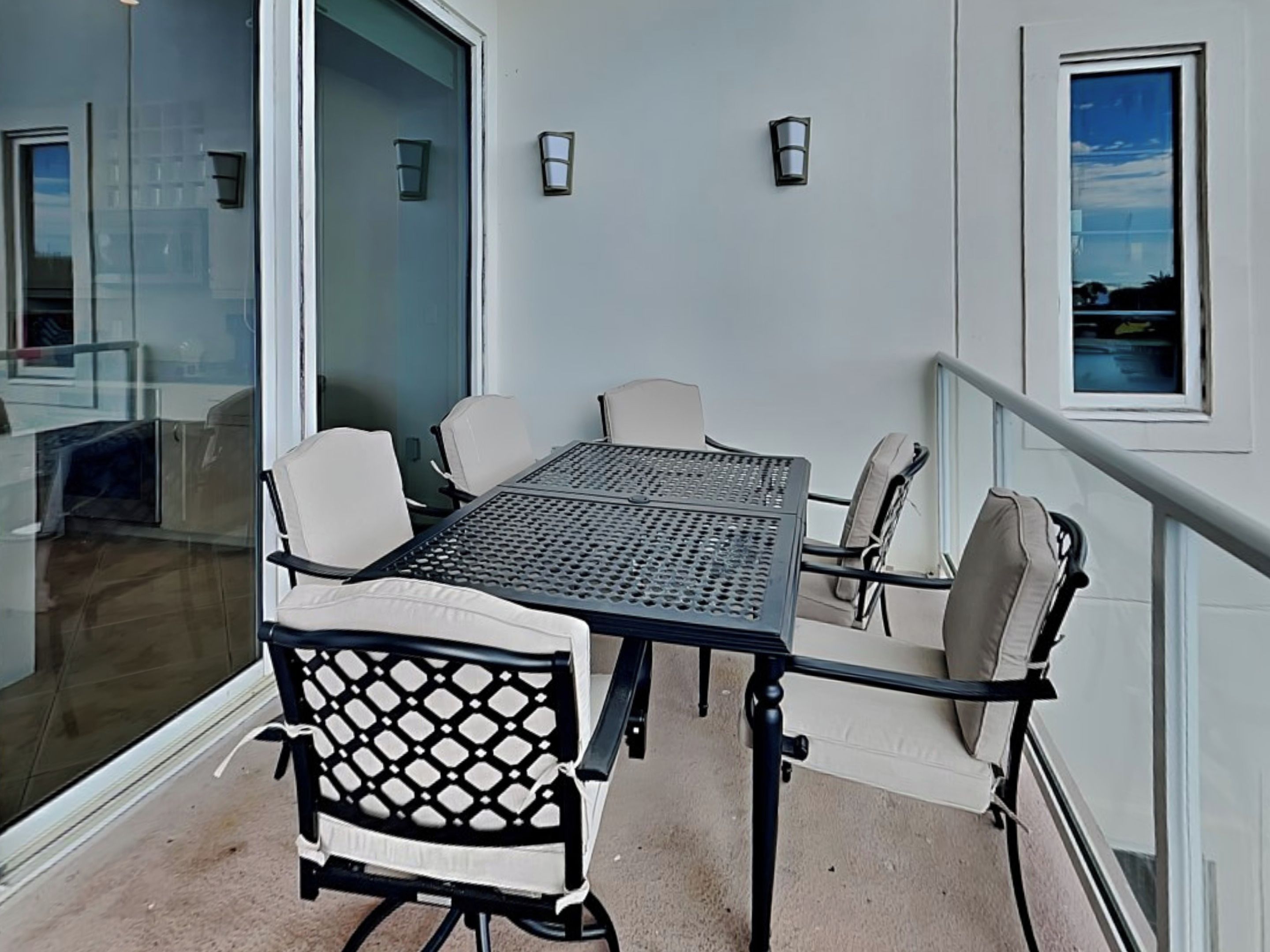 A balcony with a table and chairs, a glass door, and a railing.