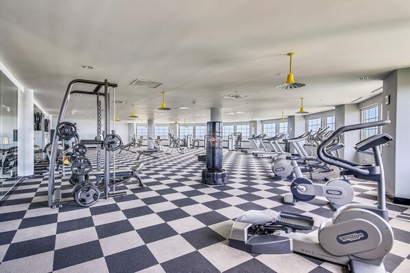 Ein Fitnessstudio mit Schachbrettfußboden, unterschiedlicher Trainingsausstattung und großen Fenstern.