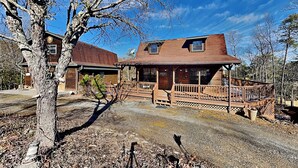 A rustic wooden cabin with a porch, a satellite dish, and a clear blue sky. - Kajun Kove by Jackson Mountain Rentals (Sevierville)