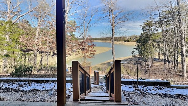 A wooden staircase leading to a viewing platform overlooking a lake, surrounded by trees and a clear sky. - Kajun Kove by Jackson Mountain Rentals (Sevierville)