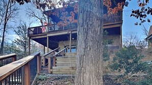 A two-story building with a wooden deck and stairs leading to a balcony. - Kajun Kove by Jackson Mountain Rentals (Sevierville)