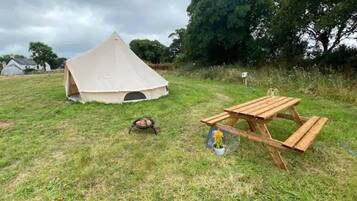 A tent set up on a grassy field with a picnic table nearby.