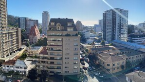 Un edificio de gran altura con varios pisos, un patio central y vistas a la calle con coches aparcados.