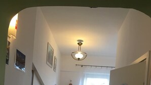 Ein schmaler Flur, am Ende ein Essbereich, ein Fenster mit Aussicht und ein Deckenventilator.