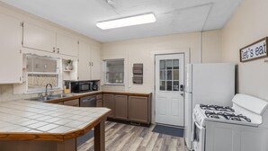 A kitchen with a tiled countertop, a stove, a refrigerator, and a sink. - HIstoric 4 BR Near Fulton St (Grand Rapids)
