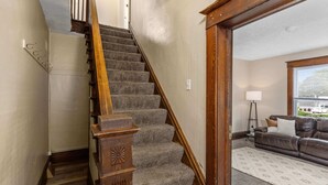 A staircase with wooden railings leading to a living room with a sofa and a lamp. - HIstoric 4 BR Near Fulton St (Grand Rapids)